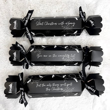 Load image into Gallery viewer, Three wrapped adult theme naughty Christmas crackers with a black and white design, featuring a bow and a card with a Christmas message.